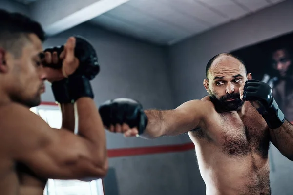 Chce to jen dokonalý úder. Vystřižený snímek dvou mužských bojovníků trénink v tělocvičně. — Stock fotografie