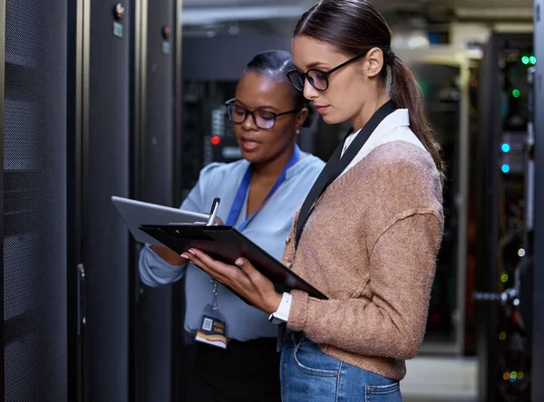 Wat voor snelheden krijg je. Gesneden opname van twee aantrekkelijke jonge vrouwelijke computerprogrammeurs die samenwerken in een serverruimte. — Stockfoto