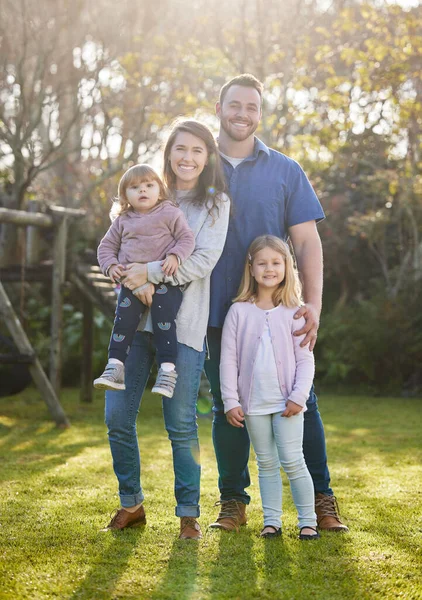 Familie is alles. Full length portret van een aanhankelijke jonge familie van vier poseren in de tuin thuis. — Stockfoto
