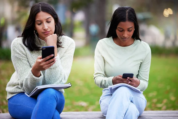 Zeit für eine Pause voneinander oder von den sozialen Medien. Aufnahme von zwei jungen Frauen mit ihren Smartphones während ihres Studiums am College. — Stockfoto