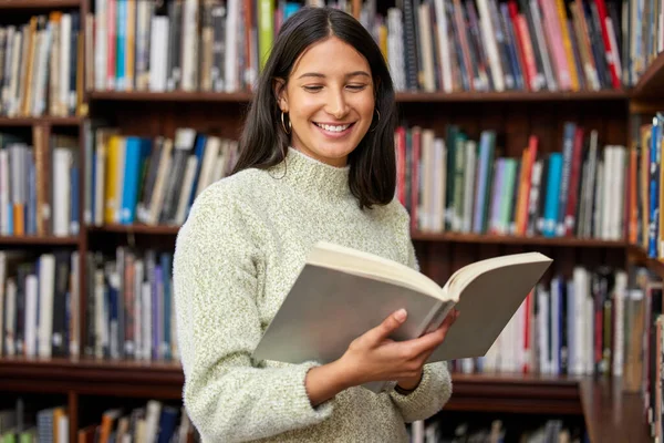 Allt du behöver för en bättre framtid. Skjuten av en ung kvinna som läser en bok i ett bibliotek. — Stockfoto