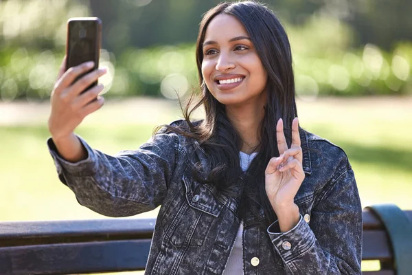 Contenuto e confortevole. Girato di una bella giovane studentessa che usa il suo telefono mentre è seduta fuori. — Foto Stock