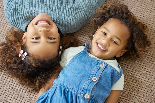 Var systrar som kom bra överens. Hög vinkel skott av två bedårande små flickor som ligger på golvet tillsammans. — Stockfoto