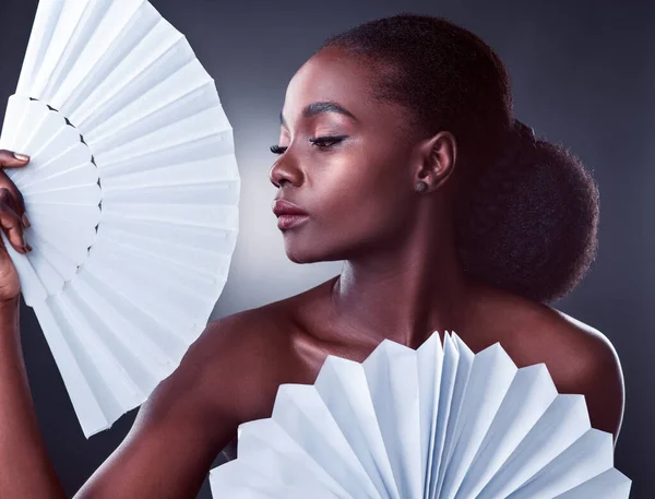 Elegance is not something that can be taught, darling. Studio shot of a beautiful young woman posing with origami fans against a black background.