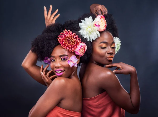 Ζήσε τη ζωή σε πλήρη άνθιση. Δύο όμορφες γυναίκες ποζάρουν μαζί με λουλούδια στα μαλλιά τους.. — Φωτογραφία Αρχείου