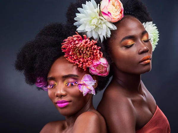 As flores são um melhor amigo das meninas. Tiro cortado de duas mulheres bonitas posando junto com flores em seu cabelo. — Fotografia de Stock