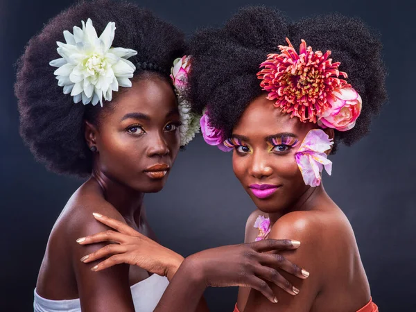 Ένα άγγιγμα της φύσης κάνει όλη τη διαφορά. Δύο όμορφες γυναίκες ποζάρουν μαζί με λουλούδια στα μαλλιά τους.. — Φωτογραφία Αρχείου