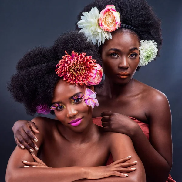 A mudança é linda. Tiro cortado de duas mulheres bonitas posando junto com flores em seu cabelo. — Fotografia de Stock