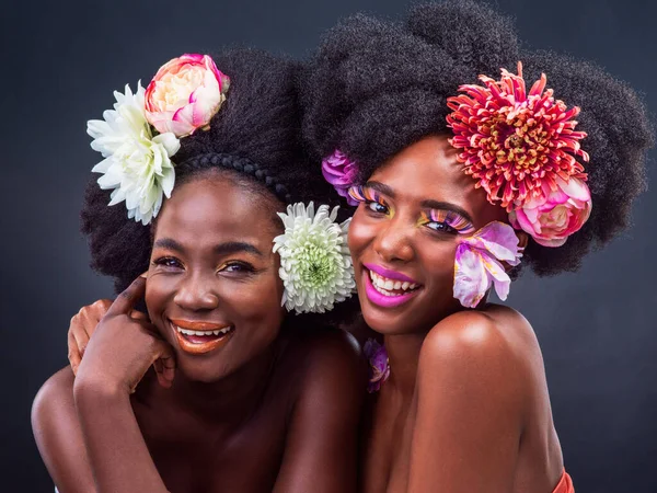 With flowers in our hair and happiness in our hearts. Cropped shot of two beautiful women posing together with flowers in their hair. — Stockfoto