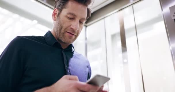 Встретимся в холле. 4k видеозаписей красивого взрослого бизнесмена, отправляющего смс во время езды на лифте на работе. — стоковое видео