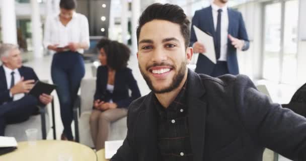君の笑顔は君のことをよく言っている。若いビジネスマンの4kビデオ映像背景に彼の同僚とオフィスで笑顔. — ストック動画