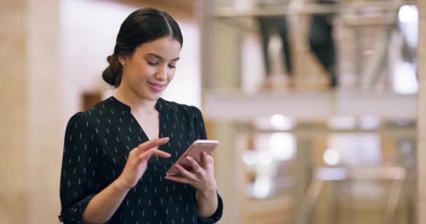 De qué se trata todo esto. Imágenes de video de 4k de una atractiva joven empresaria enviando un mensaje de texto mientras está de pie en su edificio de oficinas. — Vídeos de Stock