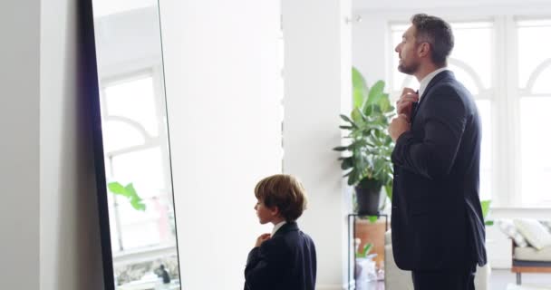 Mirror mirror on the wall, were the coolest of all. 4k video footage of an adorable little boy and his father getting dressed in matching suits at home. — Stok video