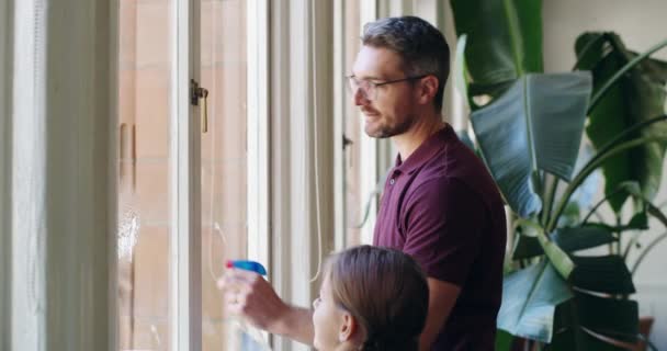 Sparkly vinduer kommer lige op. 4k video optagelser af en lille pige rengøring vinduer med sin far derhjemme. – Stock-video