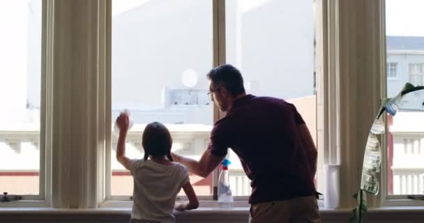 Así es como hacemos brillar el sol. Imágenes de video de 4k de una niña limpiando ventanas con su padre en casa. — Vídeos de Stock