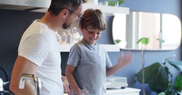 Add a dash of fun. 4k video footage of an adorable little boy baking with his father at home. — Stockvideo