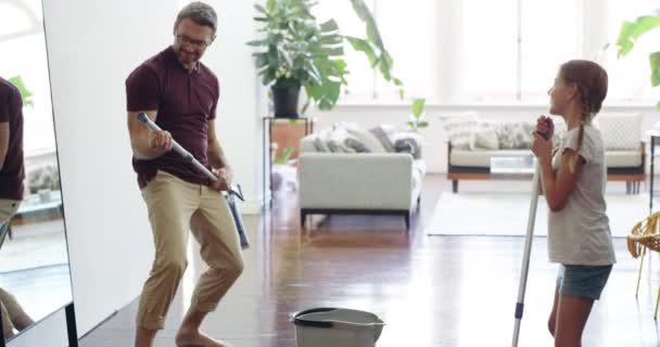 Rock out with your mop out. 4k video footage of a father singing and having fun while mopping the floor with his daughter at home. — Stockvideo