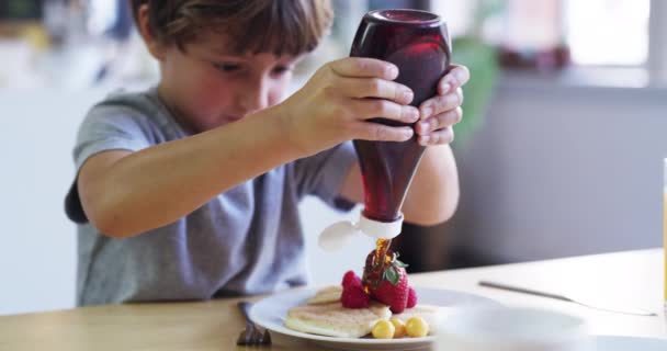 Es ist eine süße Situation. 4k Videomaterial von einem entzückenden kleinen Jungen, der zu Hause Sirup auf seine Pfannkuchen drückt. — Stockvideo