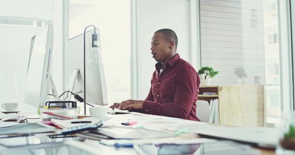 Que bom dia está a vir para o escritório. Filmagem em vídeo 4k de um jovem empresário alegre trabalhando em seu computador no escritório. — Vídeo de Stock