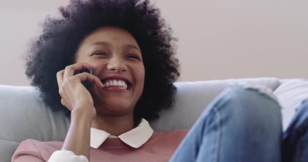 Those hour long phone calls with your bestie. 4k footage of an attractive young woman using a mobile phone while relaxing on the sofa at home. — Video