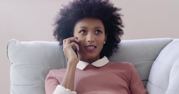 Je suis ravie que tu aies appelé. Images 4k d'une jolie jeune femme utilisant un téléphone portable tout en se relaxant sur le canapé à la maison. — Video
