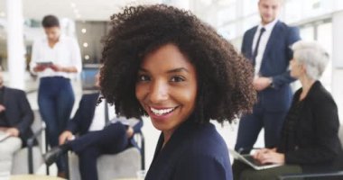 Its great to be part of such a remarkable team. 4k video footage of a young businesswoman smiling in an office with her colleagues in the background.