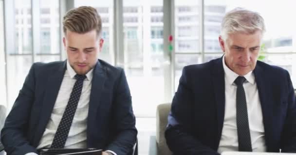 Doing the needed research before their interviews. 4k video footage of a group of businesspeople using digital devices while sitting in a line. — Stok video