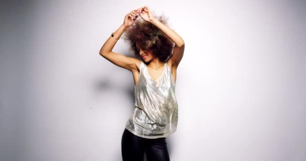 Cheerful young woman celebrating a party dancing with gold confetti in her hair. carefree young woman dancing against a white background. Happy young woman celebrating with gold confetti in her afro — Stok video