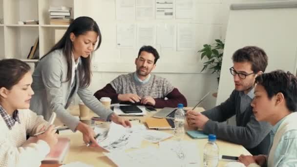 A diverse group of focused businesspeople brainstorming and looking at architectural drawings at the office. A group of young architects looking at blueprints for buildings and collaborating on ideas — Stok video
