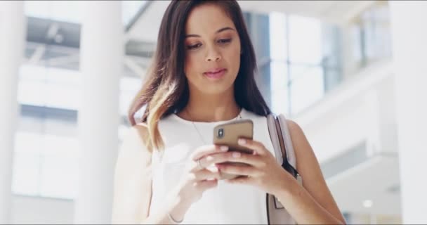 A Shell não deixou nada atrapalhar o seu sucesso. Filmagem em vídeo 4k de uma jovem empresária usando um celular enquanto caminha em um escritório moderno. — Vídeo de Stock