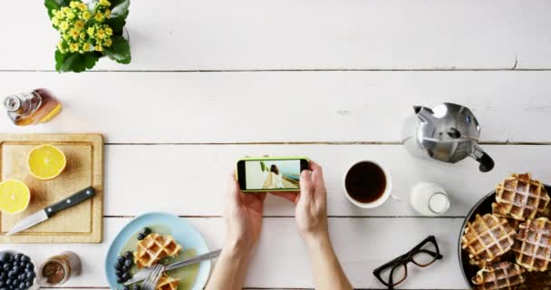 4k video footage of an unrecognisable man sitting alone in the studio and using his cellphone during breakfast — Videoclip de stoc