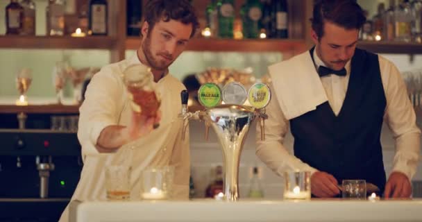 Mieszanie drinków jest tym, co robimy najlepiej. 4k video dwóch młodych mężczyzn przygotowujących drinki w barze. — Wideo stockowe