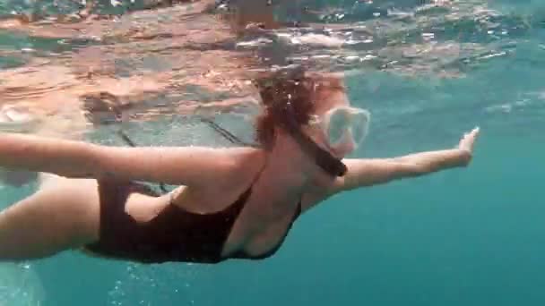 Going down under. 4k video footage of an attractive young woman waving and greeting while swimming out in the deep blue ocean. — Stockvideo