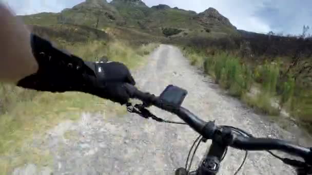 Rond de berg. 4k POV videobeelden van een man die over een onverharde weg op een berg fietst. — Stockvideo