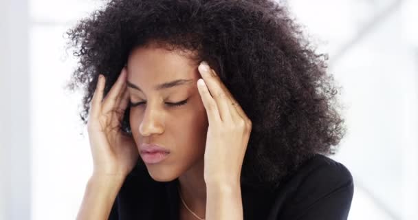As the pressure mounts. 4k video footage of a young businesswoman looking stressed while sitting in her corporate office. — Stockvideo