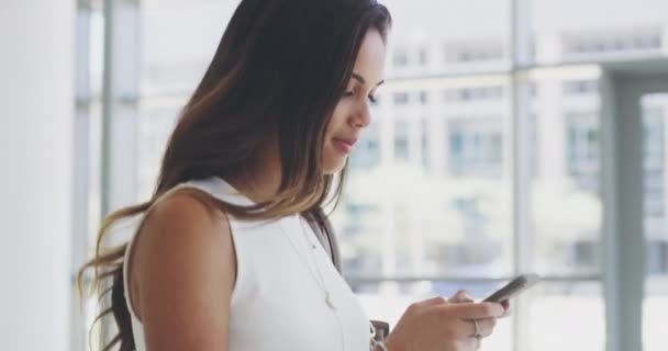Im here to achieve all my greatest dreams. 4k video footage of a young businesswoman using a cellphone while walking in a modern office. — Vídeo de stock