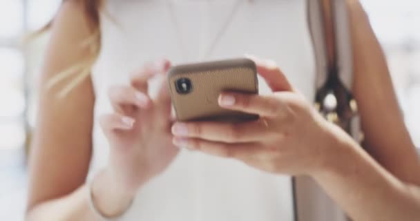Ходить со связью и уверенностью в своем шаге. 4k видеозаписей молодой предпринимательницы, использующей мобильный телефон во время прогулки в современном офисе. — стоковое видео