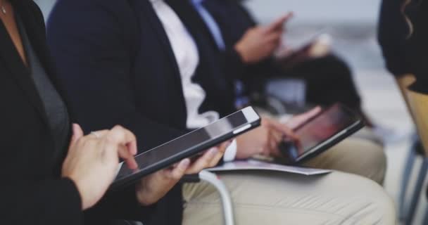 Tomando notas sobre sus dispositivos más eficientes. Imágenes de vídeo 4k de empresarios que utilizan dispositivos digitales mientras están sentados en una conferencia. — Vídeos de Stock
