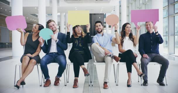 So what you thinking. 4k video footage of a group of confident young businesspeople seated next to each other while holding up speech bubbles inside of the office. — Vídeo de Stock