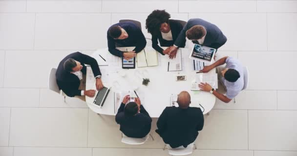 誰もが私たちに参加できることを嬉しく思います。日中仕事でテーブルの周りに会議を持っているビジネスマンのグループの高角度4kビデオ映像. — ストック動画