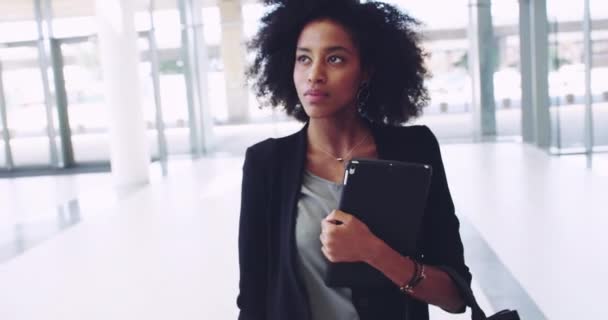 Ze stapt op een nieuwe wereld. 4k videobeelden van een zelfverzekerde jonge zakenvrouw met een digitale tablet tijdens het lopen naar het werk in een gebouw. — Stockvideo