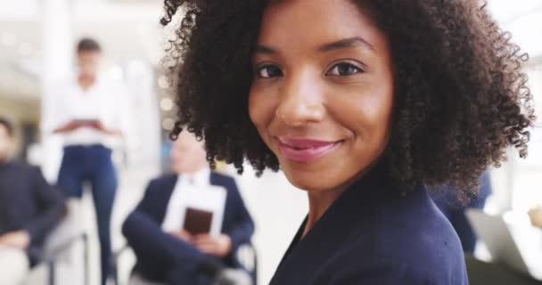 O seu entusiasmo pelo sucesso nunca acaba. Filmagem em vídeo 4k de uma jovem empresária sorrindo em um escritório com seus colegas em segundo plano. — Vídeo de Stock