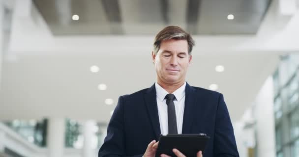 İş hayatında farkındalık şarttır, bağlantıda kalın. Modern bir ofiste yürürken dijital tablet kullanan yetişkin bir işadamının 4K video görüntüsü.. — Stok video
