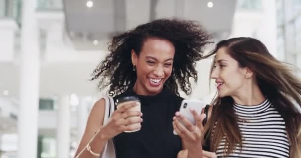 Rodéate de gente con mentalidad de éxito. Imágenes de video de 4k de jóvenes empresarias charlando y usando un teléfono inteligente mientras caminan en una oficina en una pausa para tomar café. — Vídeo de stock
