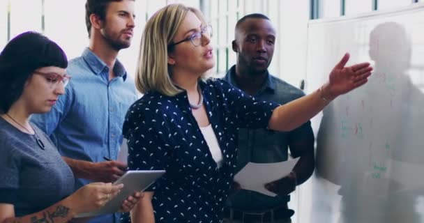 Bringing their ideas to life. 4K video footage of a diverse group colleagues brainstorming together on a whiteboard in a modern office. — Stok video