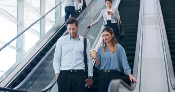 Heading out to a meeting. 4k video footage of businesspeople talking while coming down the escalator at work. — Vídeo de Stock
