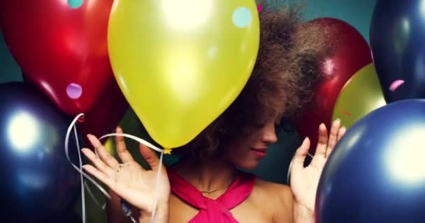 Jovem afro-americana desfrutando de uma festa dançando entre balões coloridos. Mulher despreocupada feliz dançando entre confetes coloridos e balões celebrando em uma festa — Vídeo de Stock