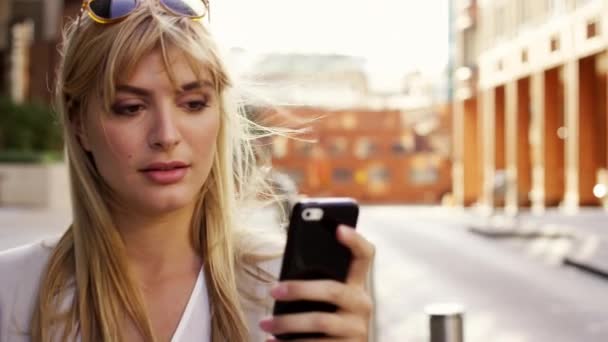 Businesswoman using her smartphone while walking to work. Young entrepreneur businesswoman thinking a sending a text message on her cellphone. Businesswoman walking in the city using her mobile phone — Stock videók