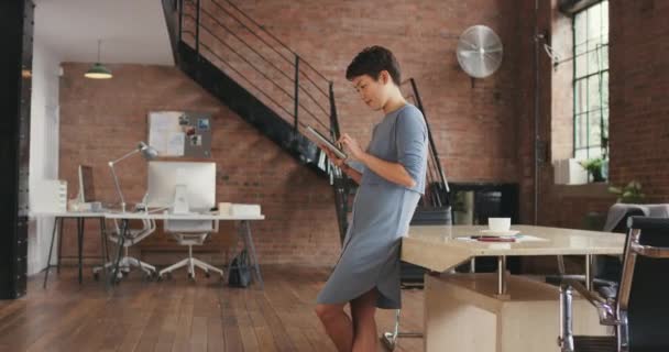 Joven empresaria que utiliza una tableta digital en una oficina moderna. Enfocado joven mujer de negocios asiática de pie en su oficina utilizando una tableta digital inalámbrica. Joven mujer de negocios utilizando aplicaciones en la tableta — Vídeo de stock