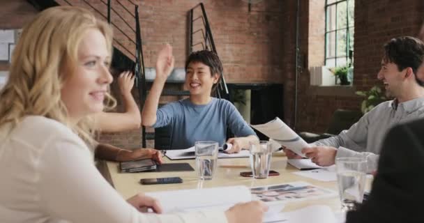 A group of businesspeople having a meeting in a modern office. diverse group of young businesspeople in a meeting, collaborate and brainstorm together. Asian businesswoman high fives a colleague — Stock videók
